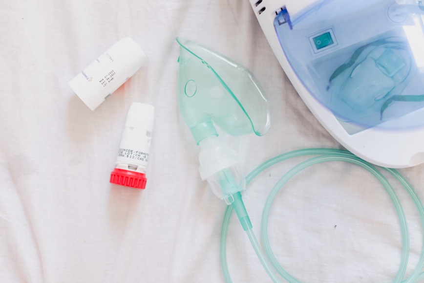 Asthma inhaler and pump on white sheet