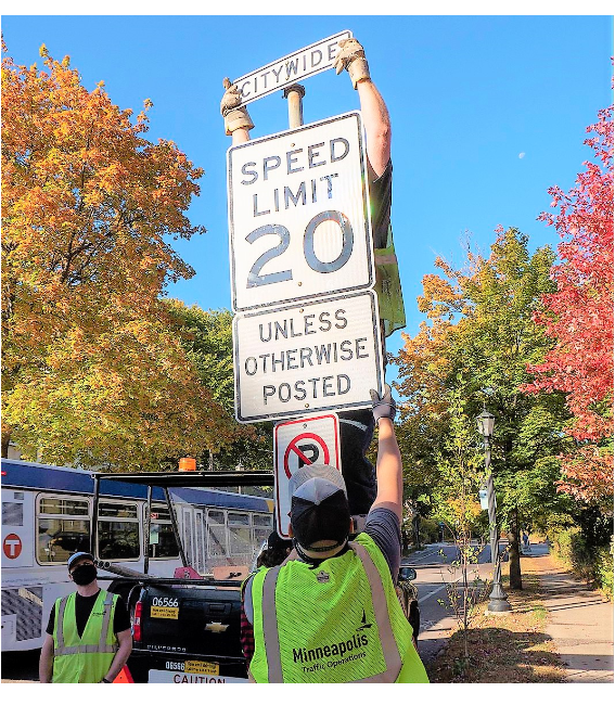 Employee installing 20 mph speed limits sign