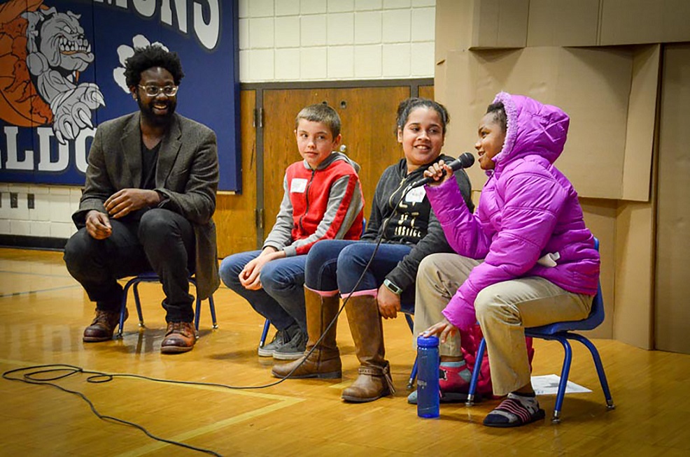 Three youth talk in microphone with adult facilitator asking questions Three youth talk in microphone with adult facilitator asking questions