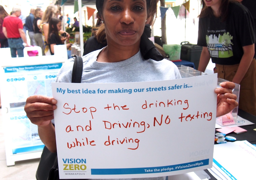Person holding sign that says: My best idea for making our streets safer is: Stop the drinking and driving. No texting while driving.