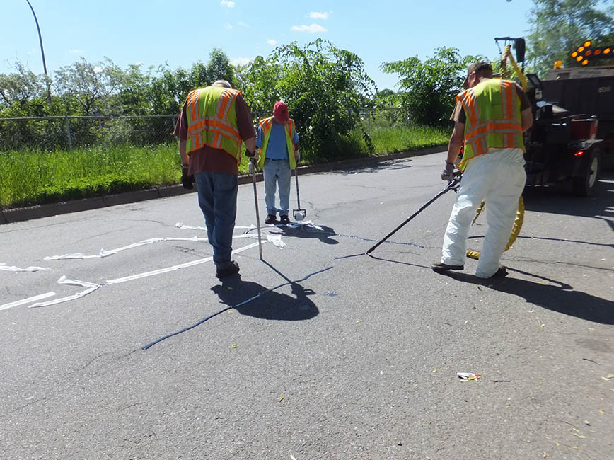 A crew works to seal cracks in the road. A crew works to seal cracks in the road.
