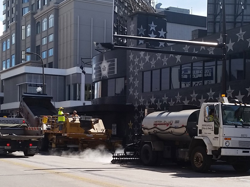 Workers seal coating a road. Workers seal coating a road.