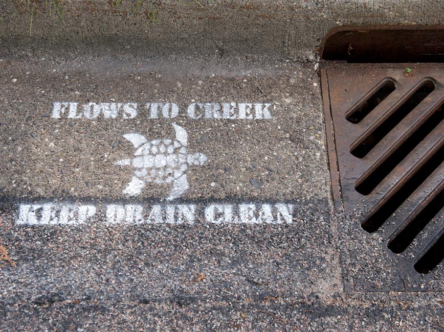 Flow to Creek Keep Drain Clean is written next to storm drain
