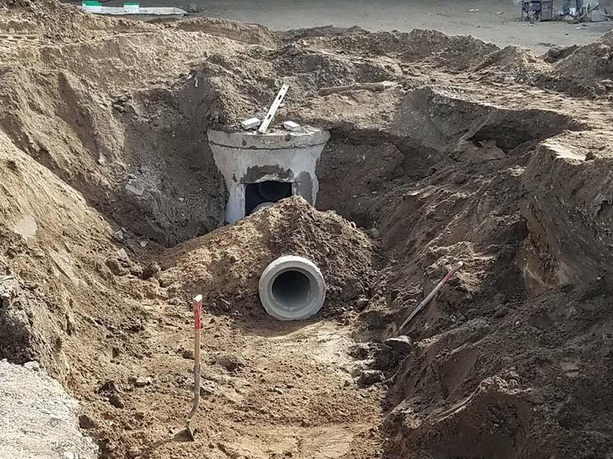 Pipe and structures installed in an excavated pit. 