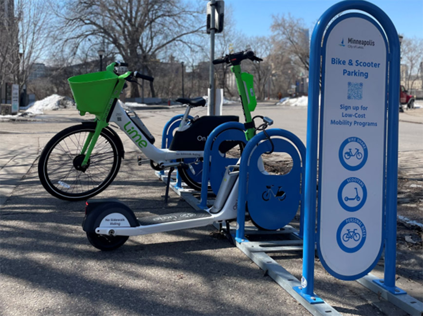 A bike and a scooter locked to a bike parking bay. A bike and a scooter locked to a bike parking bay.