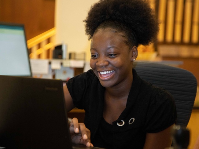 person smiling while looking at computer