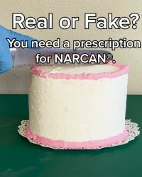 Gloved hands cutting a cake with a knife. Text at the top of the image says 