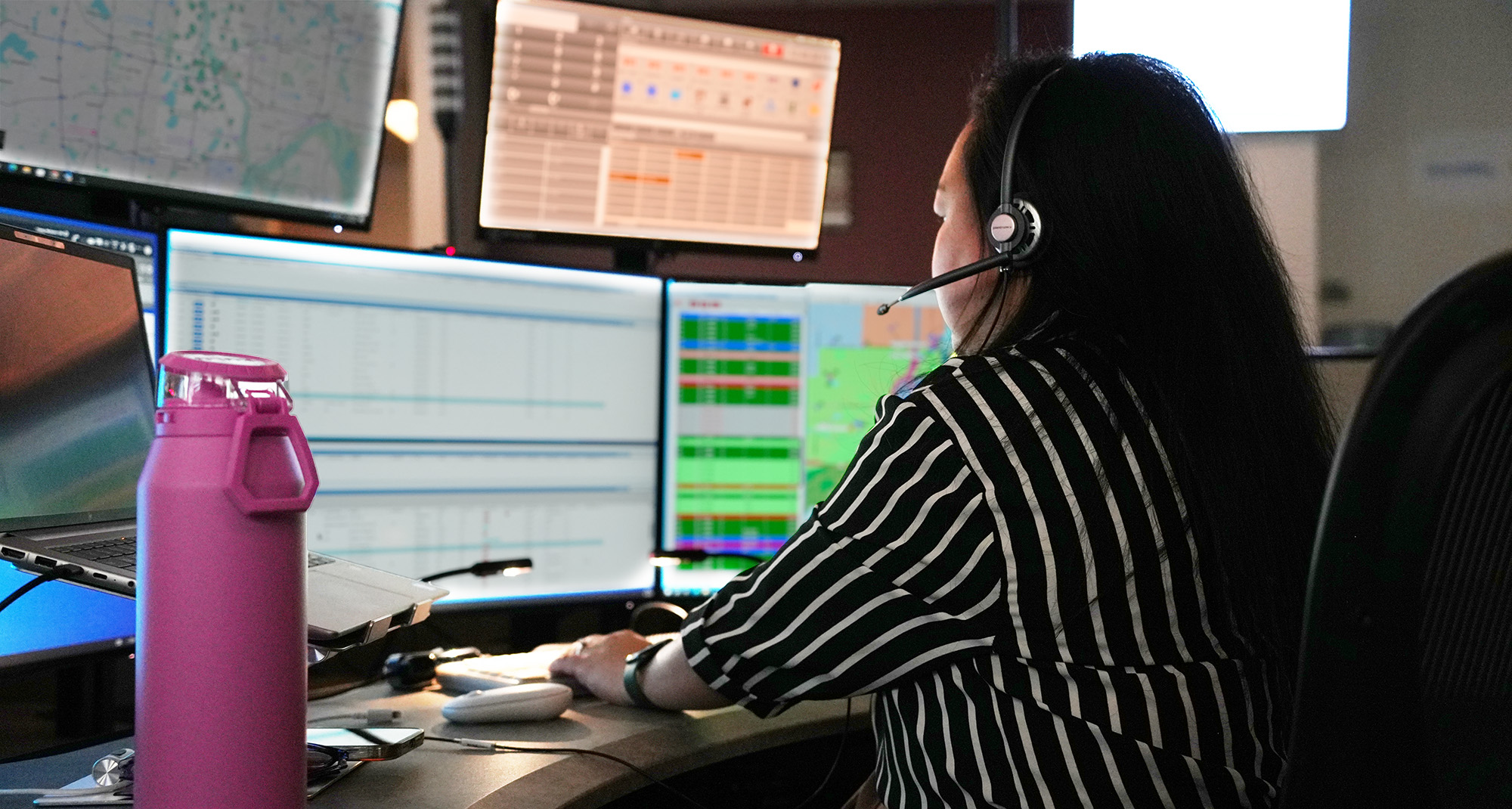 A telecommunicator wearing a headset and working at computer