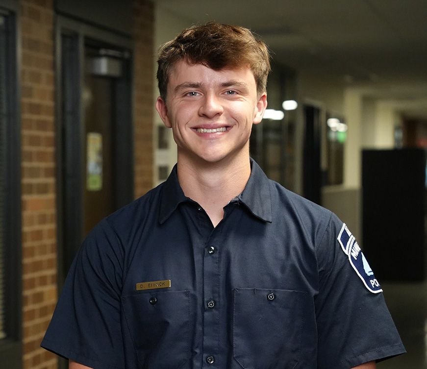 A Minneapolis police recruit smiling and standing