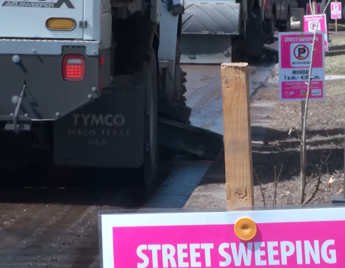 Street sweeper and pink "no parking" signs