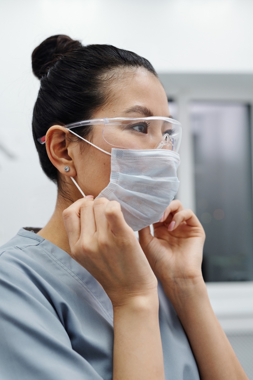 Person in scrubs wearing face mask and safety glasses.