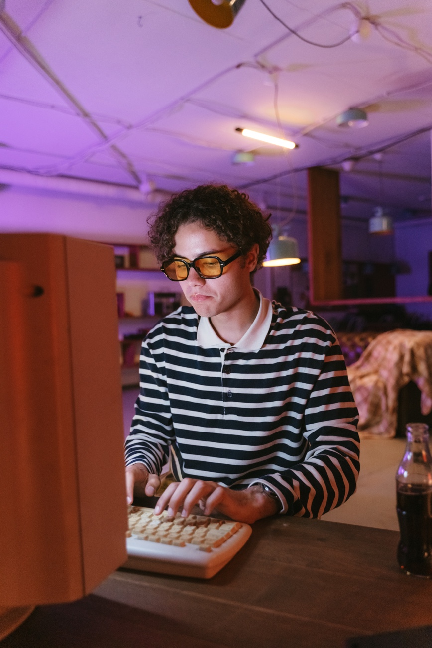 Young person in black and white long sleeve shirt wearing black framed eyeglasses.