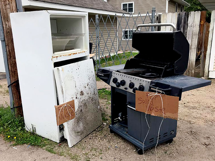 Image of refrigerator and grill set out for recycling