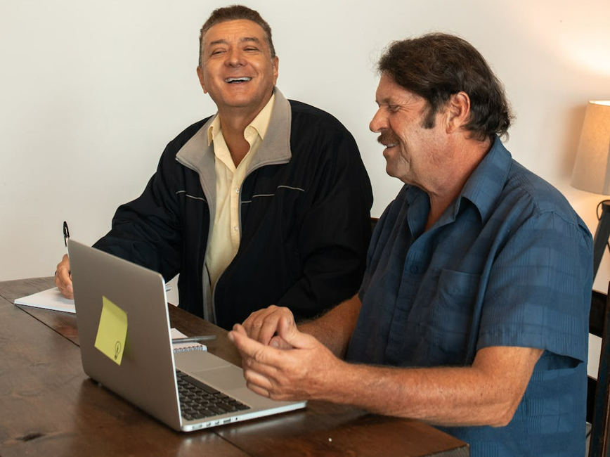Adults laughing working at laptop