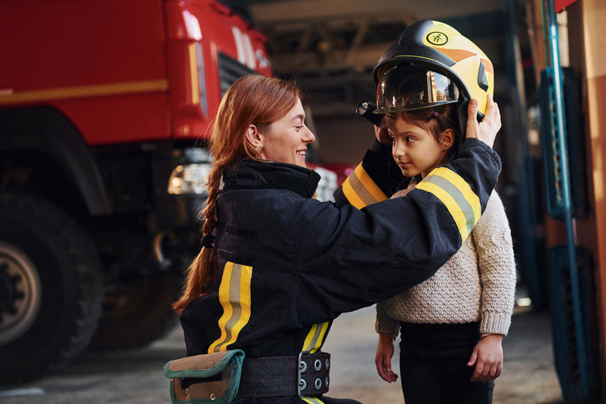 Fire fighter putting fire helmet on a child