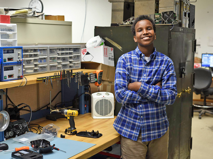 Young person in plaid standing proudly in front of workbench