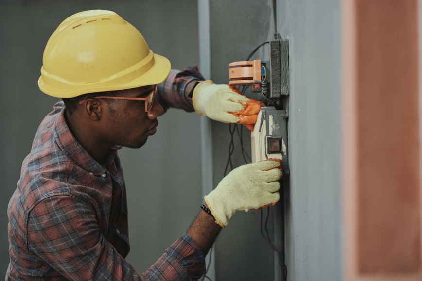 Person wearing yellow hard hat working on electrical wiring.