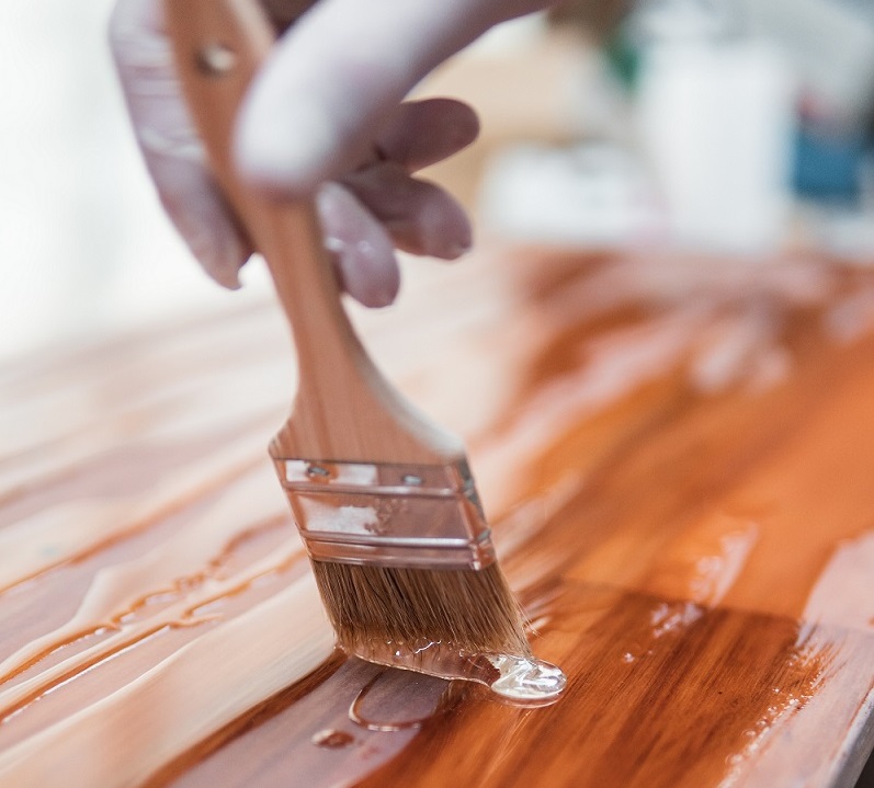 Paint brush applying resin to a wood surface