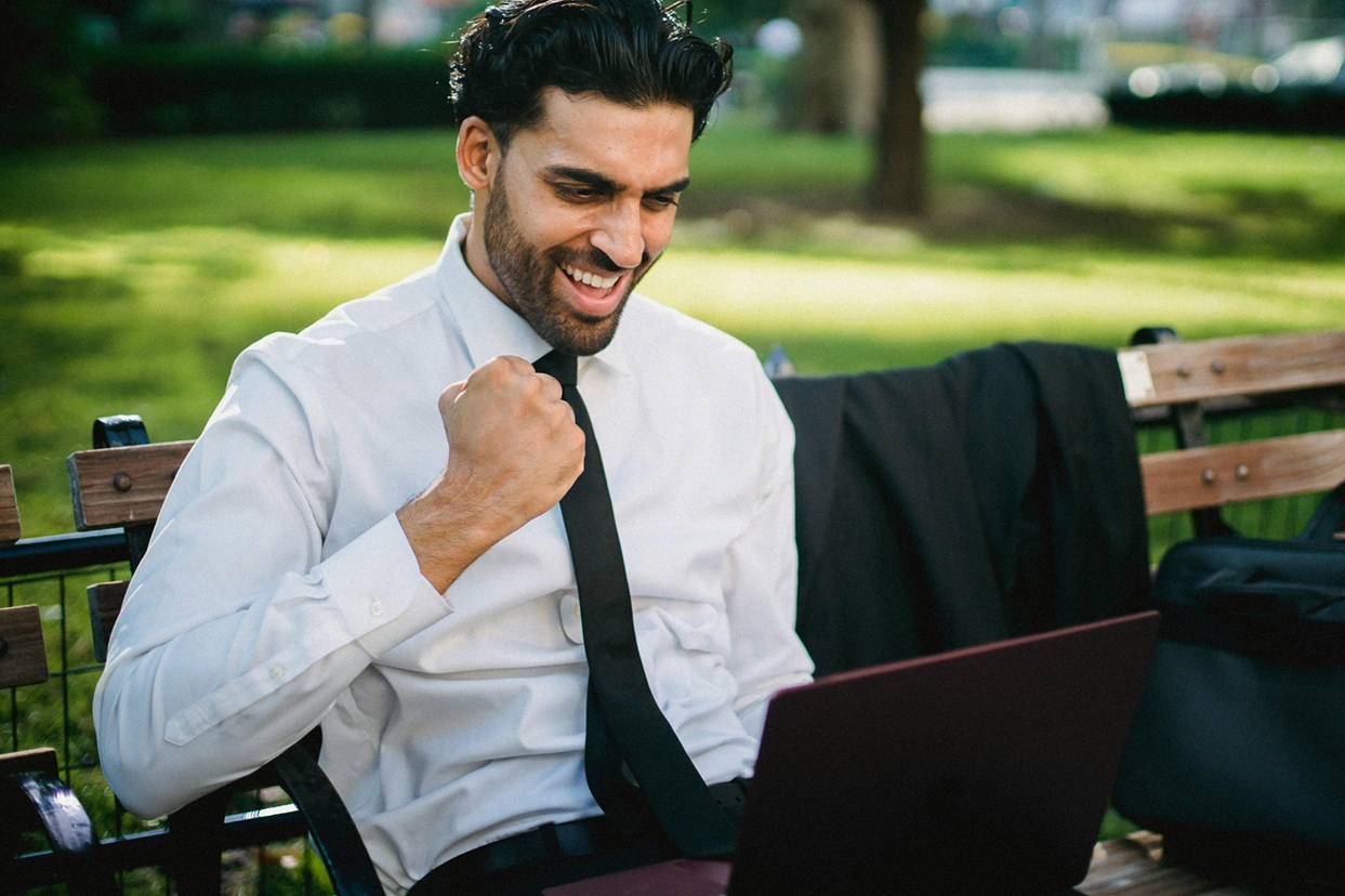 Person in white long sleeves smiling and clenching fist