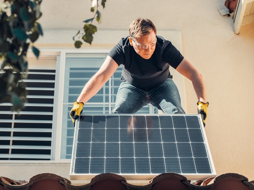 Person installing solar panels on roof