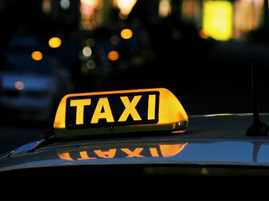 Taxi vehicle near buildings at night.